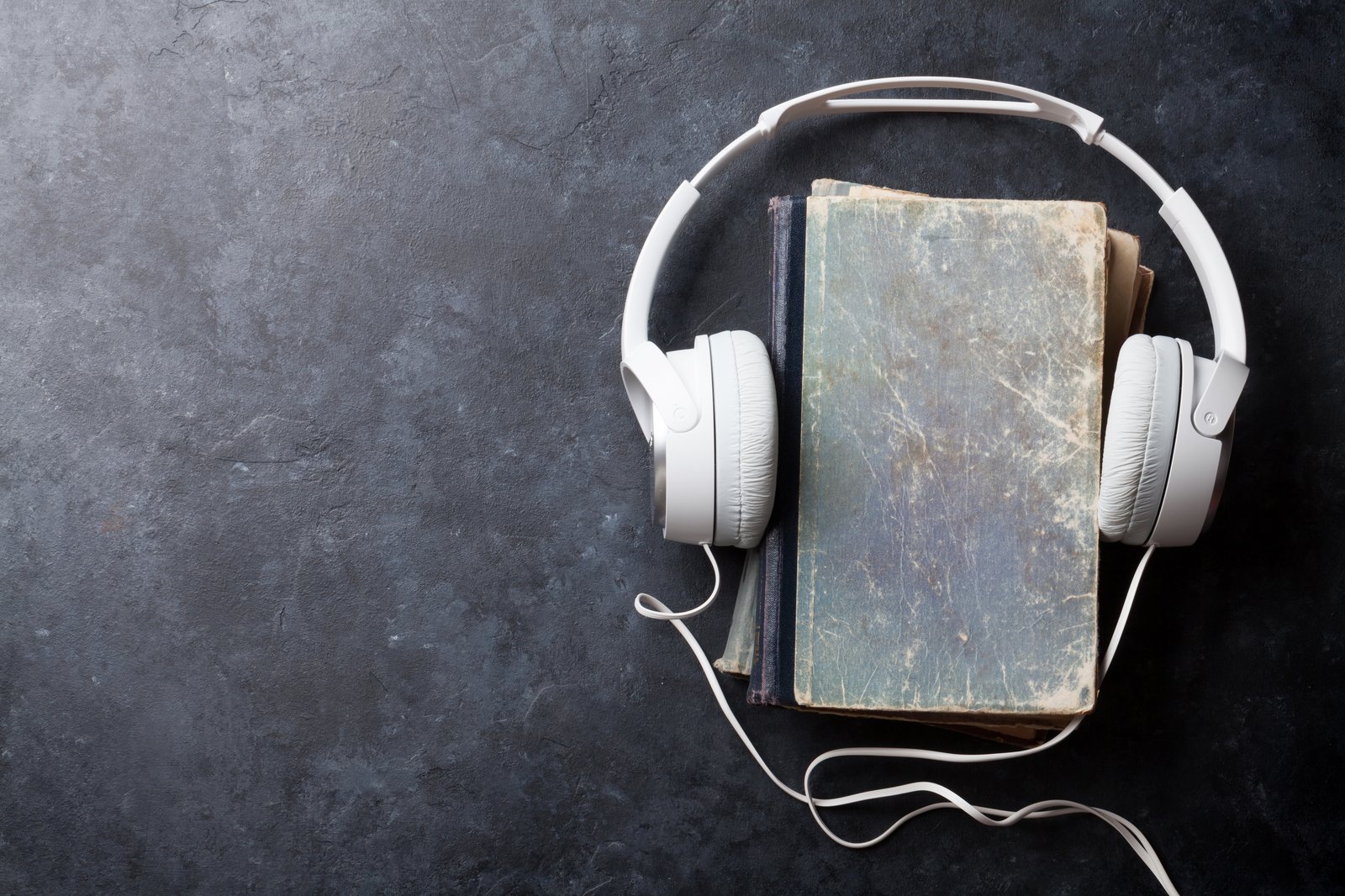 Headphones resting around well-worn books, suggesting stories carried to listeners